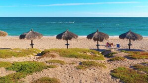 A beach with thatched umbrellas and a clear view of the ocean.