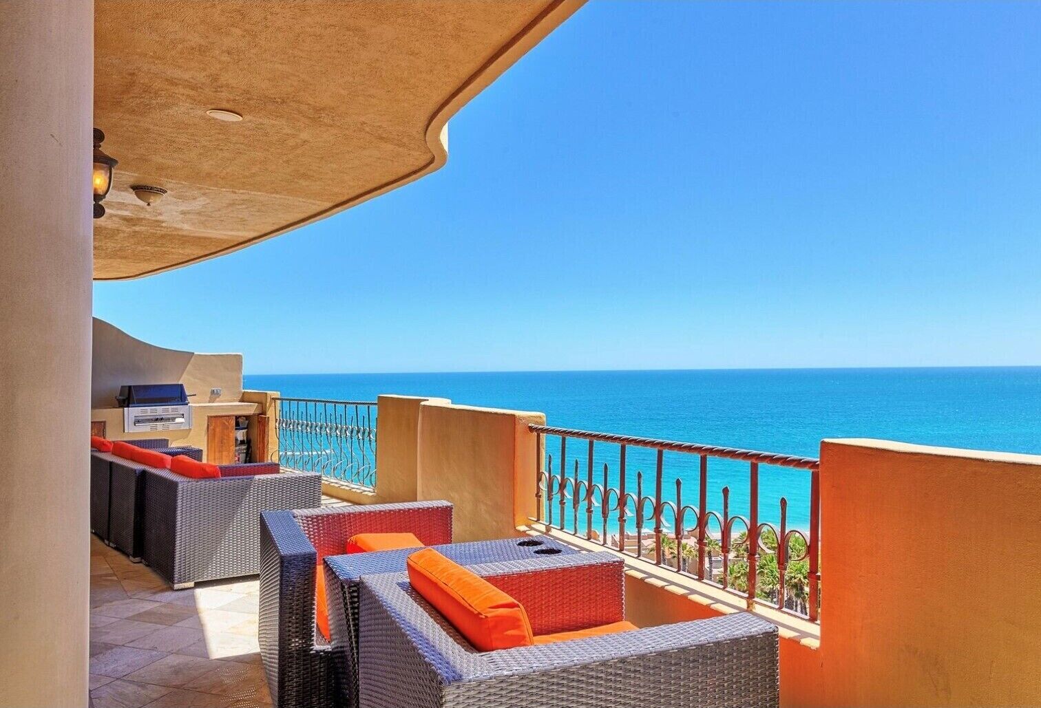A balcony with wicker furniture and a view of the sea.