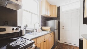 A kitchen with wooden cabinets, a stainless steel stove, a refrigerator, and a sink.