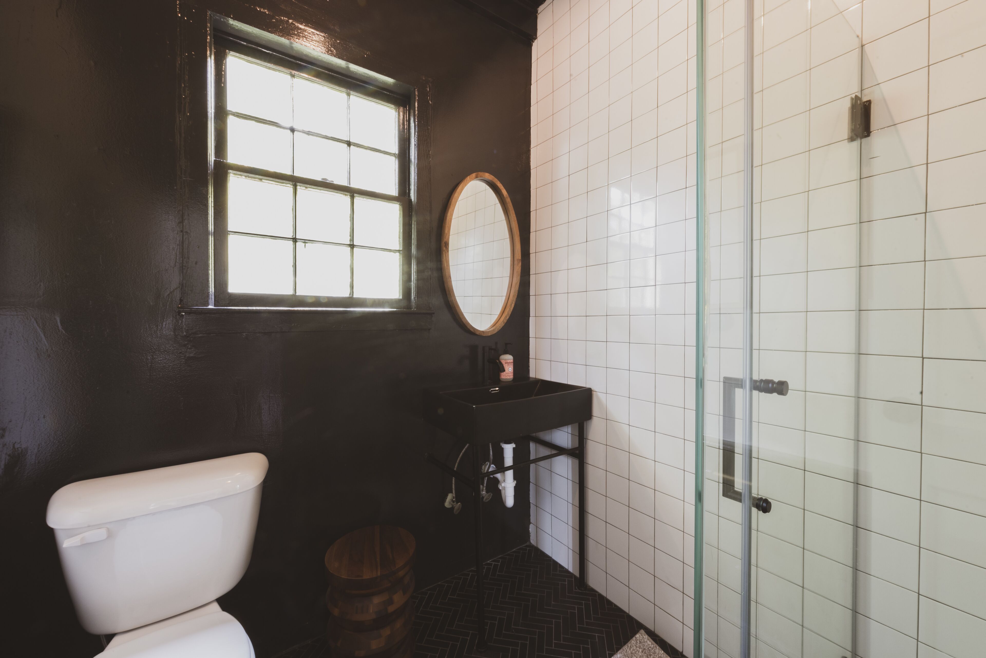 A bathroom with a toilet, a sink, a mirror, and a shower.