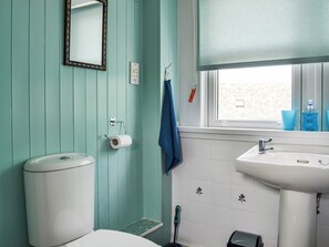 Ein Badezimmer mit Toilette, Waschbecken, Spiegel und Fenster mit Blick.