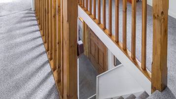 Una escalera de madera con piso alfombrado que baja a un nivel inferior.