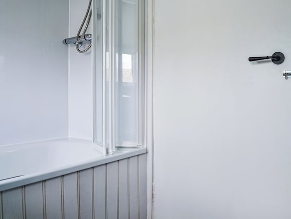A bathroom with a bathtub, a shower, and a door.