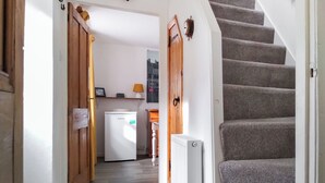 Un escalier menant à un palier où se trouvent un réfrigérateur et une lampe.