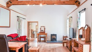 A spacious living room with wooden beams, a fireplace, a TV, and a dining area. - Slade Cottage - UK35027 (Brayford)