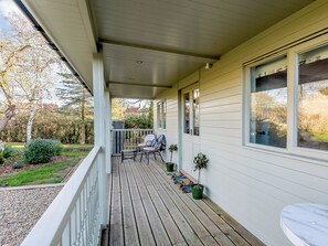 Une véranda avec une terrasse en bois, un petit coin salon et des plantes en pot.