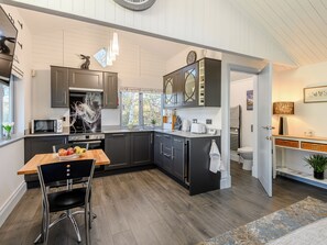 Une cuisine moderne avec des meubles de couleur sombre, un four à micro-ondes, une cuisinière et un coin repas comprenant une table et des chaises.