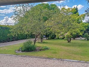 Un jardín arbolado con un camino de grava y una zona de césped.
