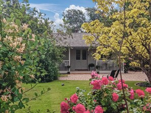 A house with a front porch, surrounded by a well-maintained garden with various plants and flowers. - 1 bedroom accommodation in Swaton (Swaton)