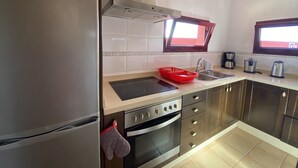 A modern kitchen with stainless steel appliances, a window above the sink, and a red dish rack. - Large villa with private heated pool (Corralejo)