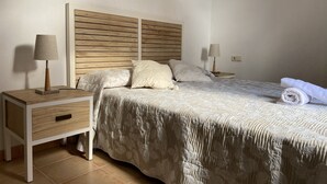 A neatly arranged bedroom with a wooden headboard, two bedside tables with lamps, a bed with a patterned bedspread, and a rolled towel on the bed. - Large villa with private heated pool (Corralejo)