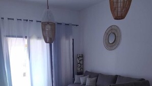 A modern living room with a sofa, a dining table, and a large window with sheer curtains. - Large villa with private heated pool (Corralejo)