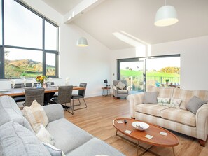 A spacious living area with a sofa, a coffee table, and a dining table set for four.