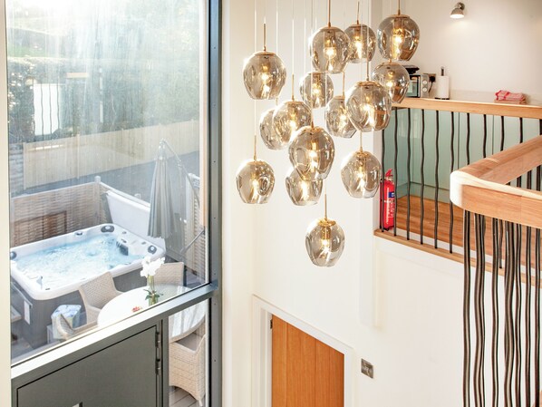 A modern interior with a hot tub, multiple hanging spherical light fixtures, and a wooden staircase.