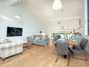 Ein großzügiger Wohnbereich mit Esstisch, Sofas und einer Küche im Hintergrund.
