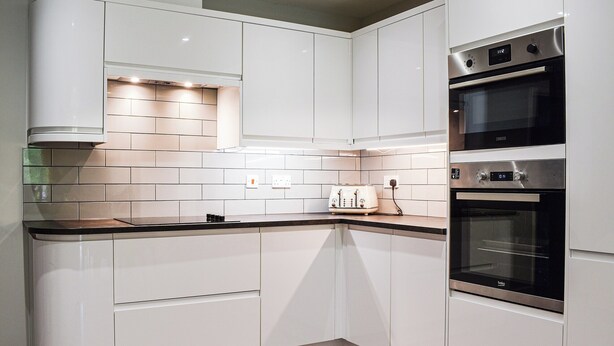A modern kitchen with white cabinetry, a built-in oven, and a toaster. - Between the forest and the sea (New Milton, near Lymington)