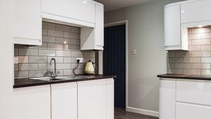 A modern kitchen with white cabinets, a black countertop, and a tiled backsplash. - Between the forest and the sea (New Milton, near Lymington)