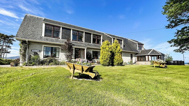A two-story house with a large front lawn, a driveway, and a garage. - Fourpenny Cottage - UK34744 (Skelbo, near Dornoch)