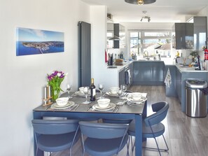 A modern kitchen with a dining area set for four. - Seagulls view is a modern 3 bedroom house sleeping up to 5 guests. (Brixham)