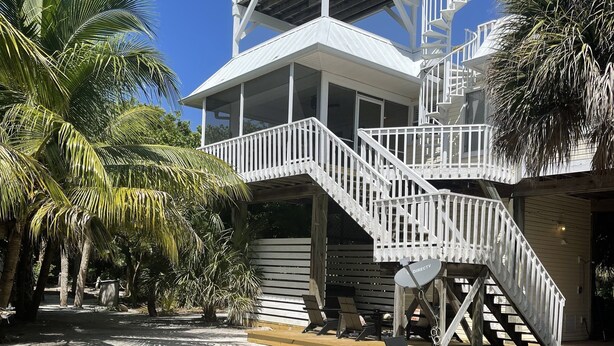 Una casa de varios niveles con fachada blanca, una escalera y una zona de terraza.