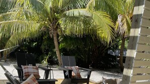 Una terraza de madera con mobiliario exterior, incluyendo una mesa y sillas, y una hamaca.