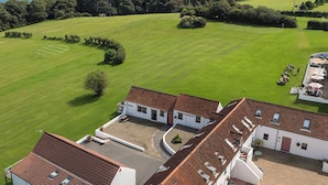 A golf course with a clubhouse and a view of the sea. - Seascape Cottage - UK6725 (Lydstep, near Tenby)