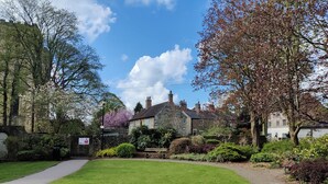 A stone building with a paved pathway leading to it, surrounded by well-maintained grass and trees. - 2 bedroom accommodation in Ripon (Ripon)