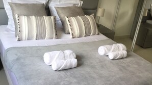 A neatly made bed with a grey blanket, two white towels, and striped pillows. - Cannes Villa center pool spa classified (Cannes)