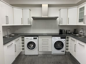 A compact kitchen with white cabinets, a double sink, a Bosch washing machine, and a toaster. - Cannes Villa center pool spa classified (Cannes)