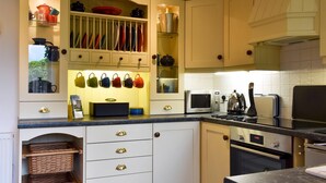 Een moderne keuken met witte kastjes, een ingebouwde magnetron, een fornuis en een koffiezetapparaat.
