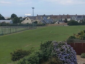 Ein grünes Feld mit einem Tor, umgeben von Häusern und einem Schiff in der Ferne.