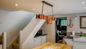 Uma cozinha com uma mesa de madeira, armários brancos e uma escada.
