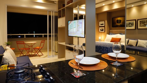 A modern hotel room with a dining area, a TV, and a balcony with a view of the city at night. - #3 Sophisticated Studio on Boaventura Da Silva (PA)
