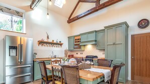 A kitchen with a stainless steel refrigerator, wooden dining table, and green cabinets.
