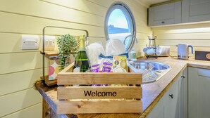 A kitchen with a wooden welcome sign, a window with a view, a sink, and various kitchen items. - A hidden gem in the stunning Ayrshire countryside. (Straiton, near Maybole)