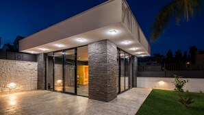Una casa moderna con ingresso a vetro, pilastri in pietra e tetto piatto.