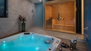 Een moderne spa-ruimte met een bubbelbad, een sauna en een houten wand met een glazen deur.