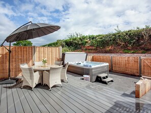 A wooden deck with a hot tub, wicker furniture, and a patio umbrella. - 3 bedroom accommodation in Over Stowey, near Bridgwater (Over Stowey, near Bridgwater)