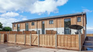 A modern building with a wooden facade, large windows, and a covered outdoor seating area. - 3 bedroom accommodation in Over Stowey, near Bridgwater (Over Stowey, near Bridgwater)