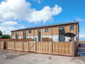 A modern building with a wooden facade, large windows, and a covered outdoor seating area. - 3 bedroom accommodation in Over Stowey, near Bridgwater (Over Stowey, near Bridgwater)