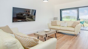 A living room with a sofa, coffee table, and a painting on the wall. - 3 bedroom accommodation in Over Stowey, near Bridgwater (Over Stowey, near Bridgwater)