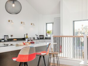 A modern kitchen with a central island, bar stools, and a view of the outdoors.