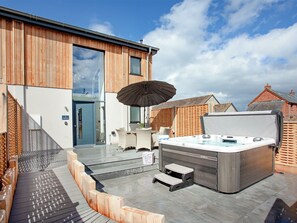A modern outdoor hot tub area with steps leading to a covered seating area.