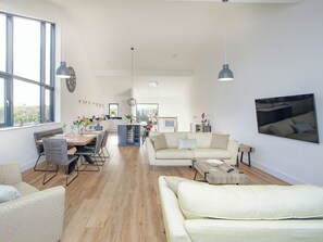 A modern living room with a sofa, dining area, and kitchen.