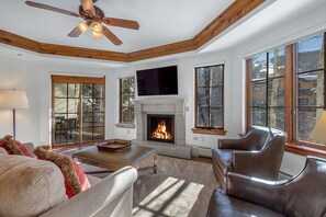 A living room with a fireplace, leather furniture, and large windows.