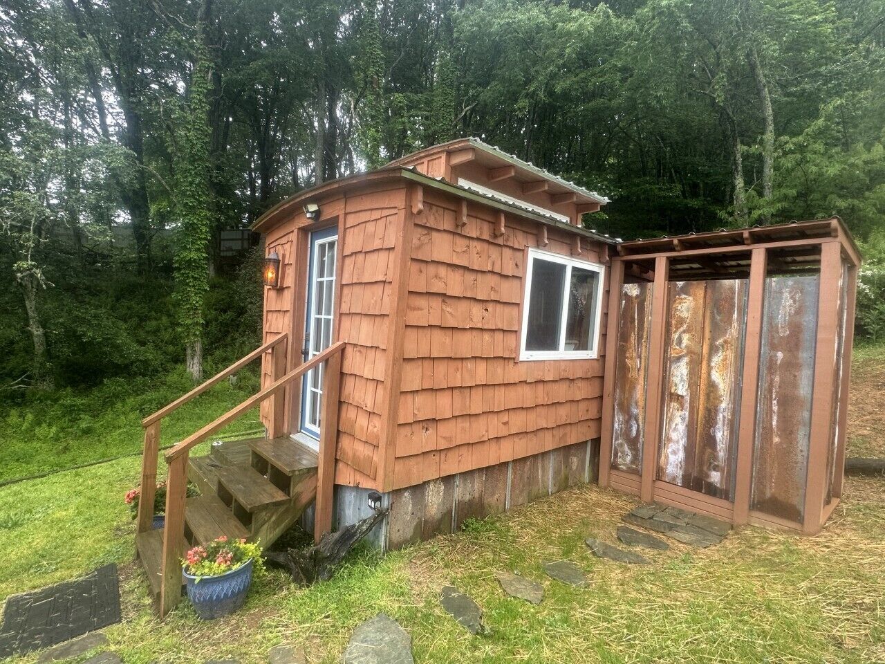 Eine kleine Holzhütte mit Veranda und einer Treppe zum Eingang.