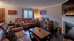 A living room with a brown leather sofa, a wooden coffee table, and a fireplace. - PRIME Location with Hot Tub, Pool Table and Sauna (Columbus)