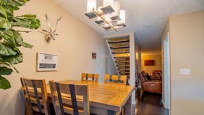 A dining area with a wooden table and chairs, a WiFi sign, a deer head decoration, and a staircase leading to another room. - PRIME Location with Hot Tub, Pool Table and Sauna (Columbus)