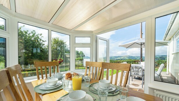 Ein Esstisch ist gedeckt mit Tellern, Gläsern und Croissants, mit Blick auf eine malerische Landschaft.