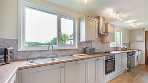 Eine moderne Küche mit großem Fenster, Einbauofen und Waschmaschine.